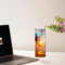 This photo shows the sunset beach tumbler sitting on desk beside laptop in cozy work setting
